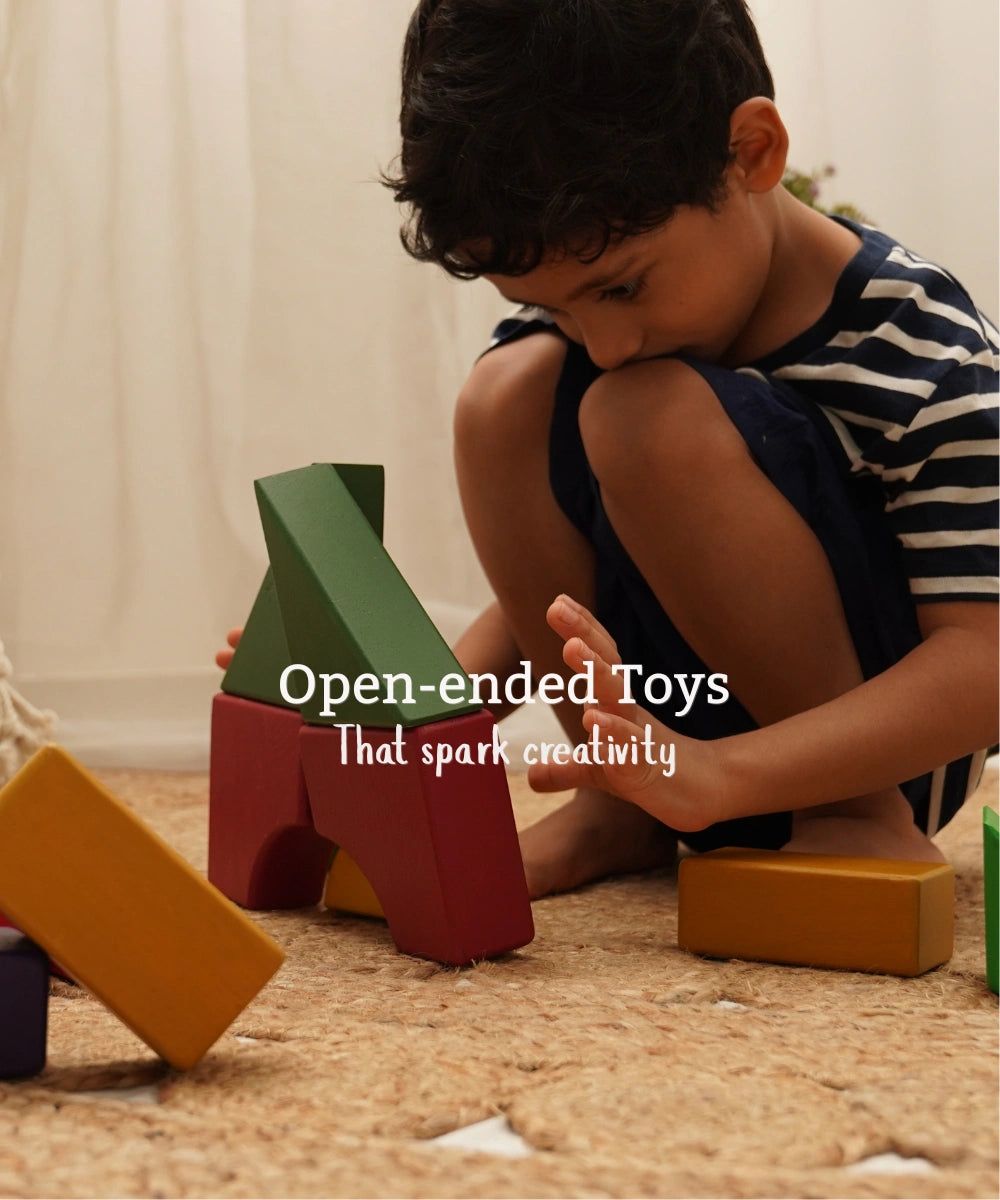 Boy playing with colourful open-ended wooden blocks on a jute rug, with the text open-ended toys that spark creativity