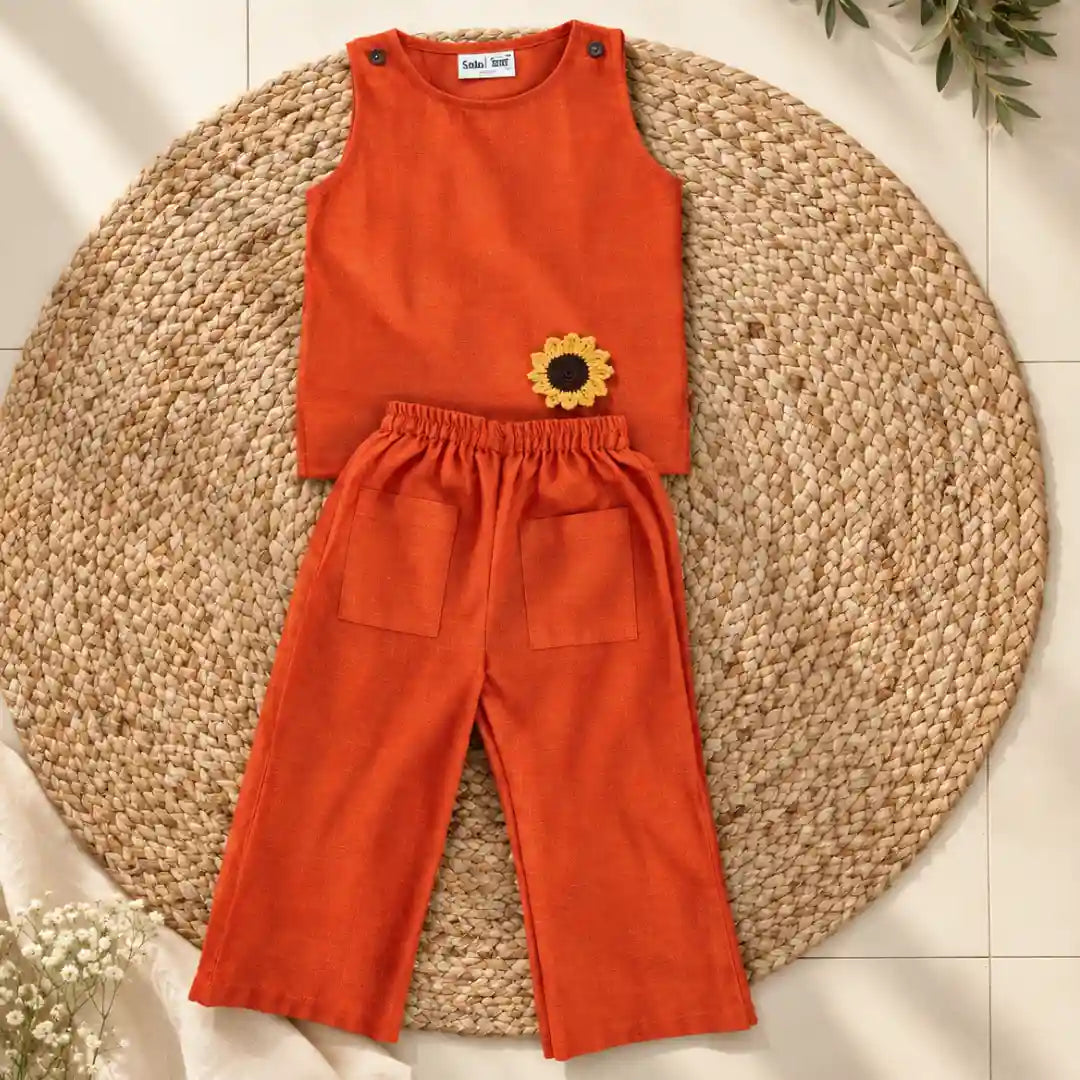 Flat lay of a rust orange ikat coord set: sleeveless top with crochet sunflower and wide-leg pants with pockets