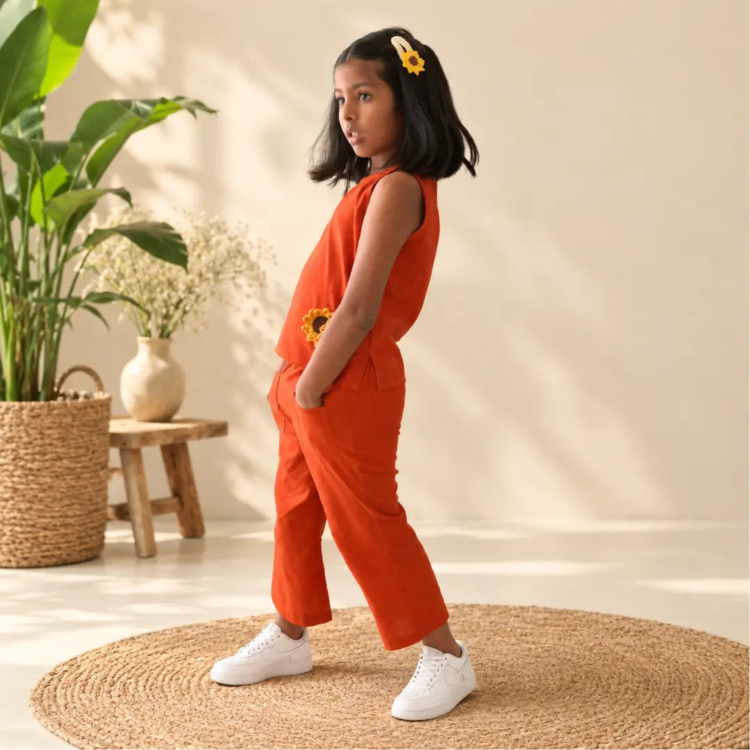 Side view of a girl in a rust orange ikat coord set with her hands in the front pockets of her wide-leg pants