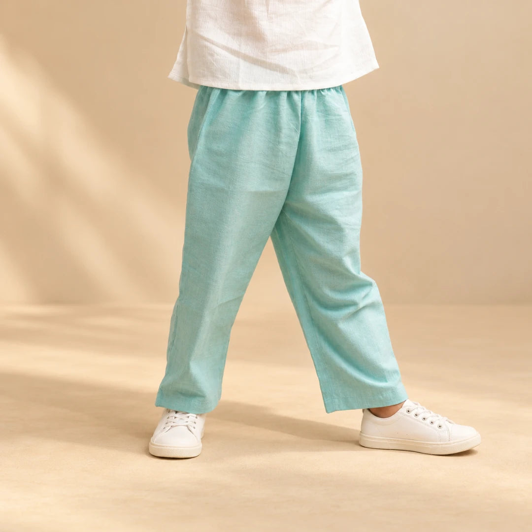 Child wearing teal blue handwoven cotton pants with a white top and white sneakers
