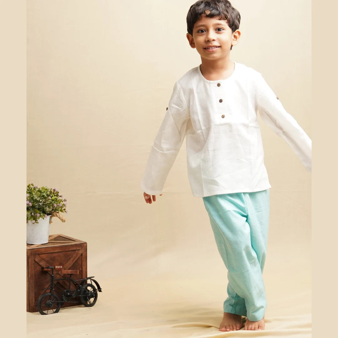 Child walking barefoot in teal blue unisex cotton pants and a white full sleeve kurta