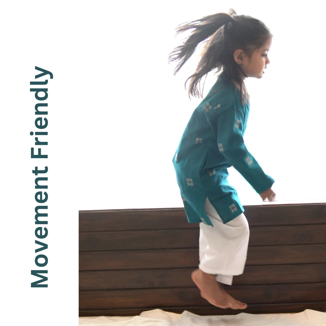 Girl in a teal kurta and white pajama jumping off a bench, showing the set is movement friendly