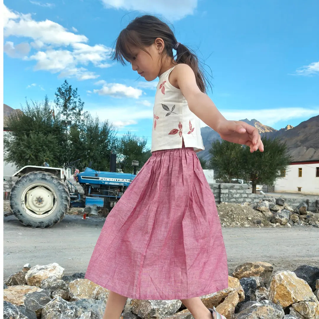 Child in a pink skirt standing on rocks with a scenic background